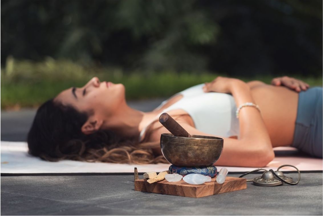 Femme allongée en relaxation, bol chantant et palo santo